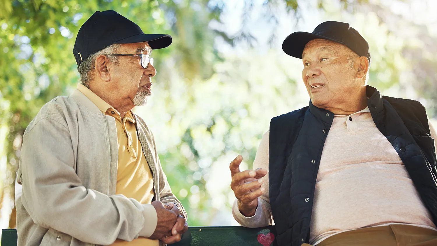 Two men sitting on a park bench and talking to each other